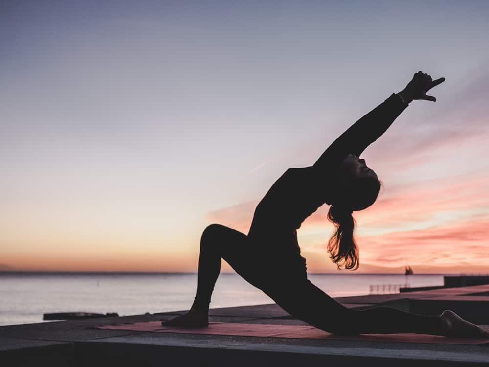 Silueta de una persona haciendo una postura de yoga al atardecer