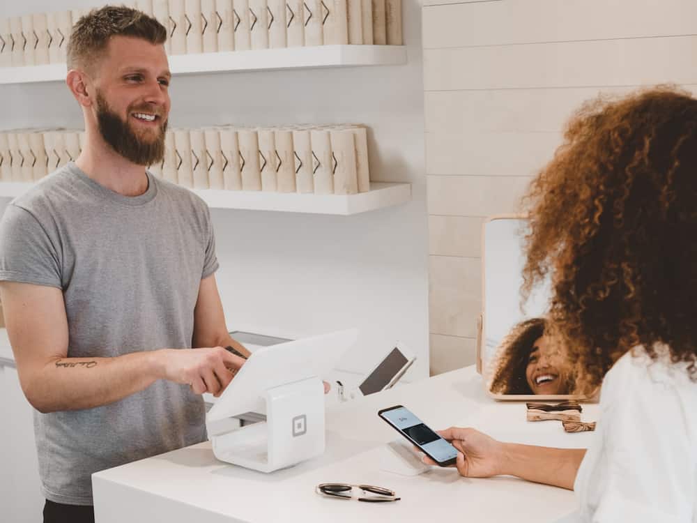 Comerciante cobrando con un datáfono a una clienta en el mostrador de su tienda