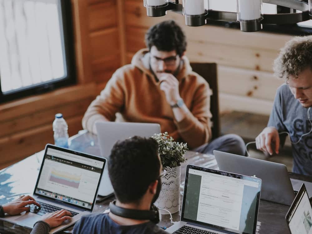 Varias personas trabajando con portátiles en una mesa compartida